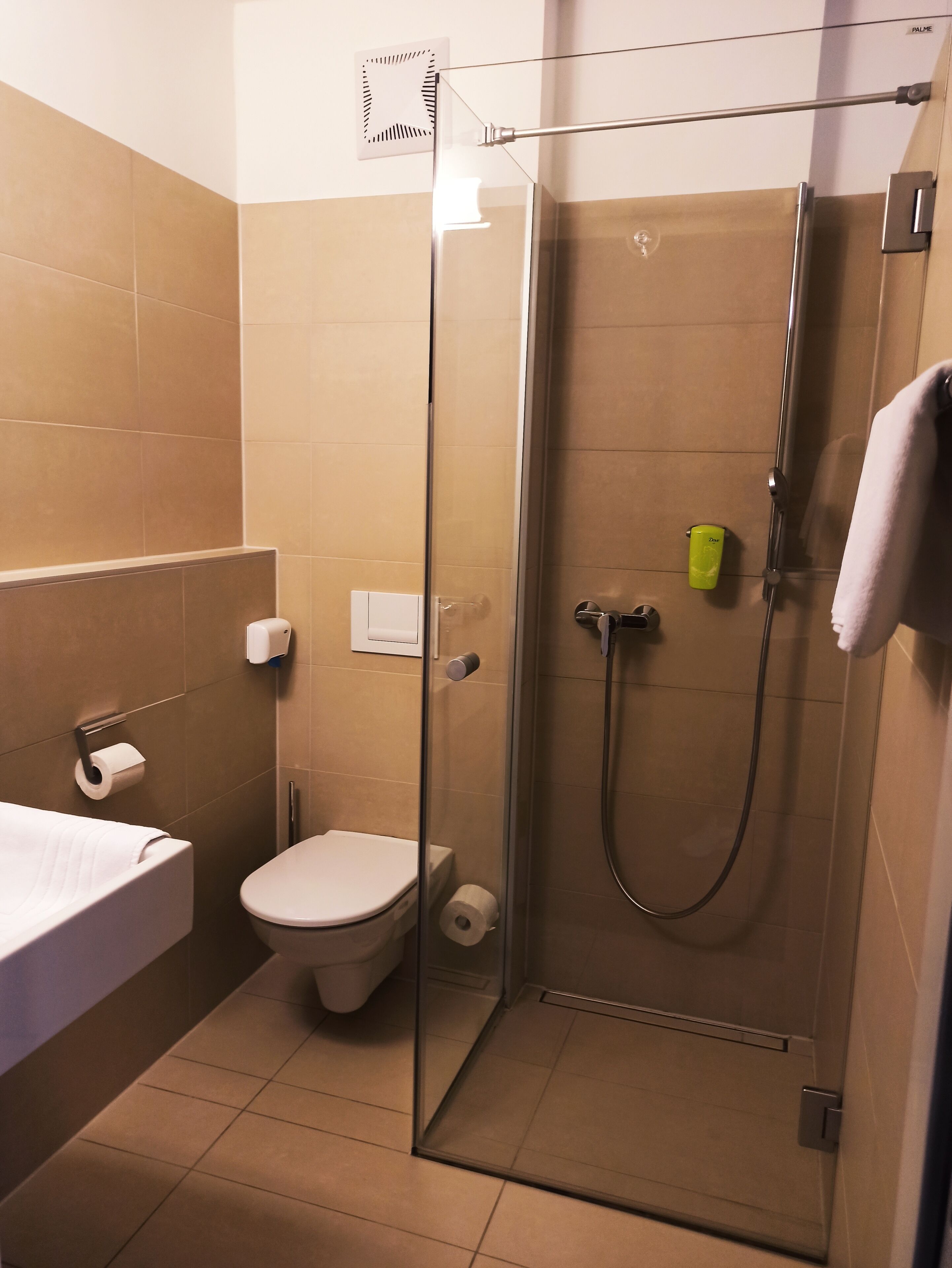 Un baño moderno con ducha de mampara de vidrio, inodoro y lavamanos.