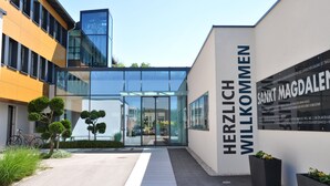 A modern building with a glass entrance and a sign reading "HERZLICH WILKOMMEN". - Sankt Magdalena (Linz)