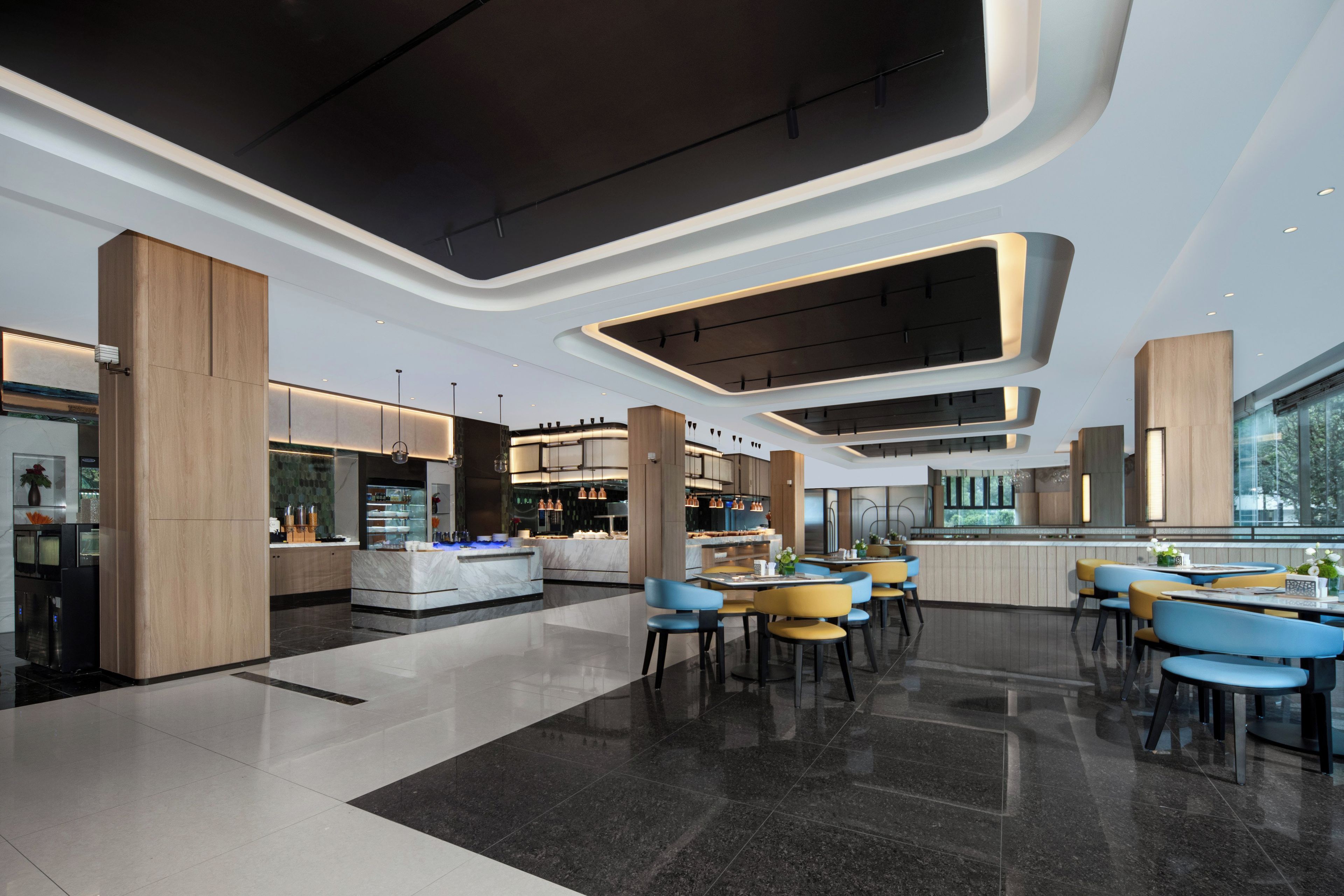 A modern interior with a central bar area, seating arrangements, and a kitchen visible in the background.