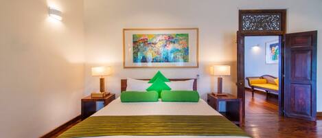 A hotel room with a large bed, two bedside lamps, a painting on the wall, and a wooden door.