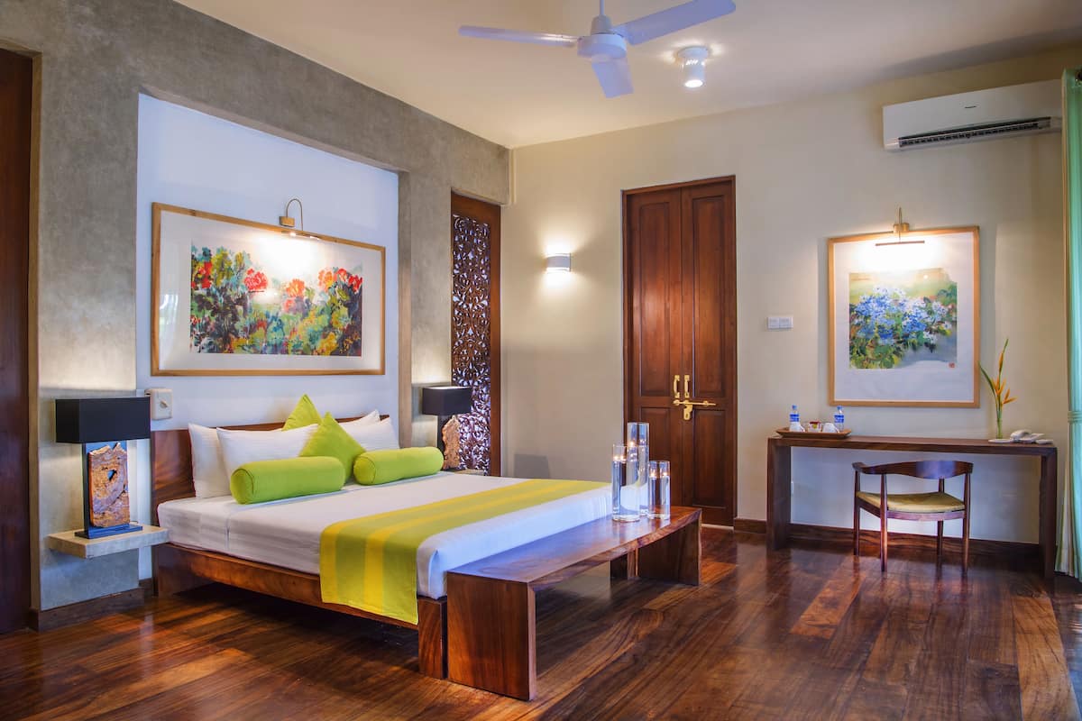 A hotel room with a bed, a desk, a chair, and artwork on the walls.
