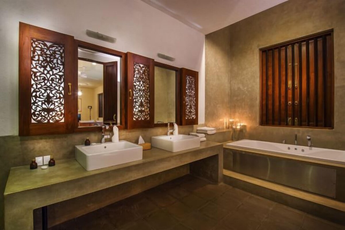 A modern bathroom with three sinks and a large bathtub.