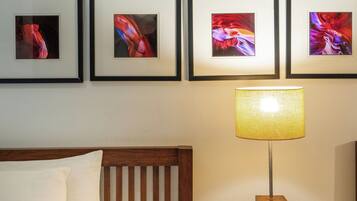 Une chambre d’hôtel avec un lit, une table de chevet avec une lampe et un mur orné de tableaux.