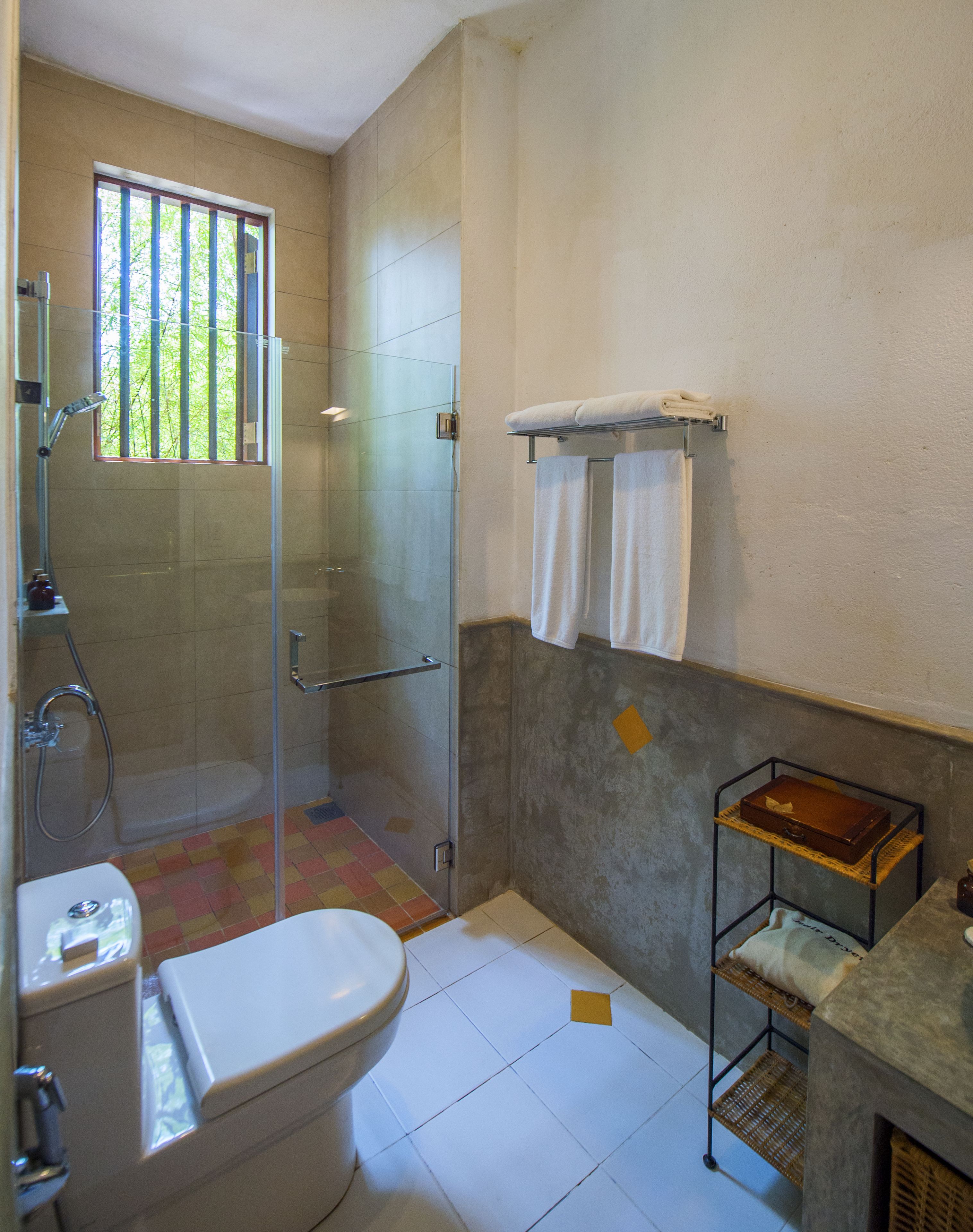 Un baño con inodoro, ducha y un pequeño estante con una caja.