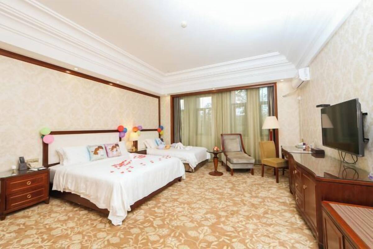 Quarto de hotel com duas camas, televisão, escrivaninha e uma cadeira.