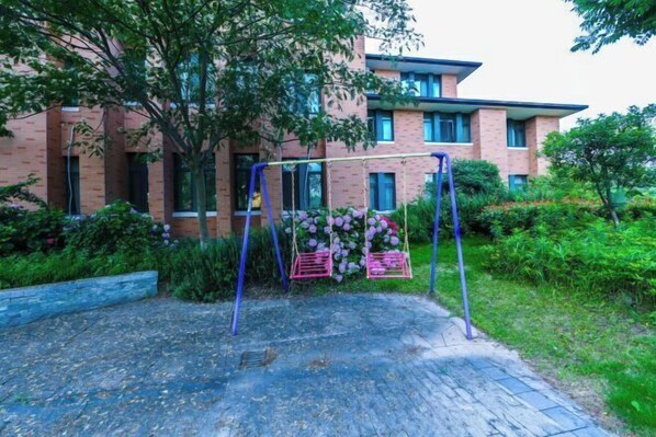 A brick building with a swing set in front. - Meiyuan Hotel (Ningbo)