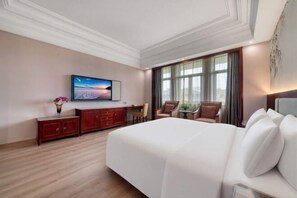 A hotel room with a large bed, a TV on the wall, a desk with a chair, and a window with curtains. - Meiyuan Hotel (Ningbo)