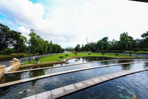 A tranquil outdoor setting with a water feature, well-maintained greenery, and a clear sky. - Meiyuan Hotel (Ningbo)