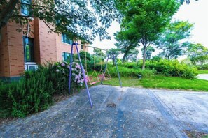 A brick building with a swing set in a landscaped area. - Meiyuan Hotel (Ningbo)