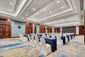 A conference room with rows of tables and chairs, a stage, and a large screen. - Meiyuan Hotel (Ningbo)