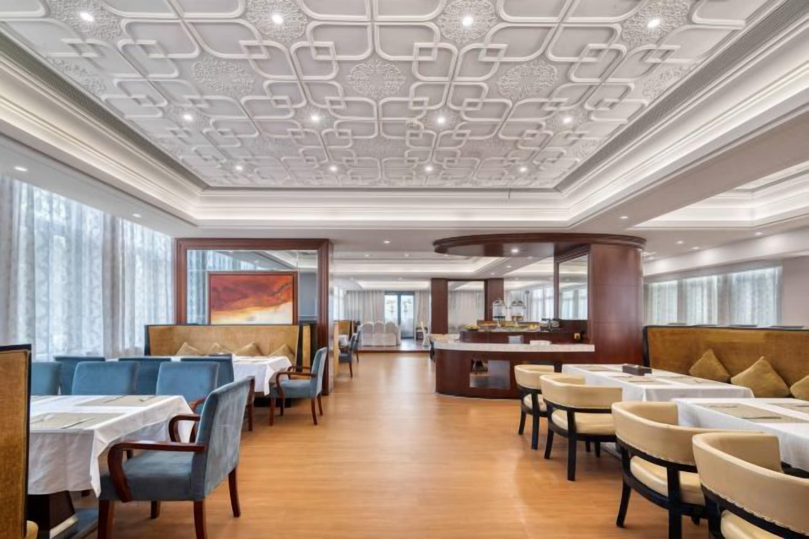 Un amplio vestíbulo de hotel con techo alto, varias zonas de estar y un bar central.