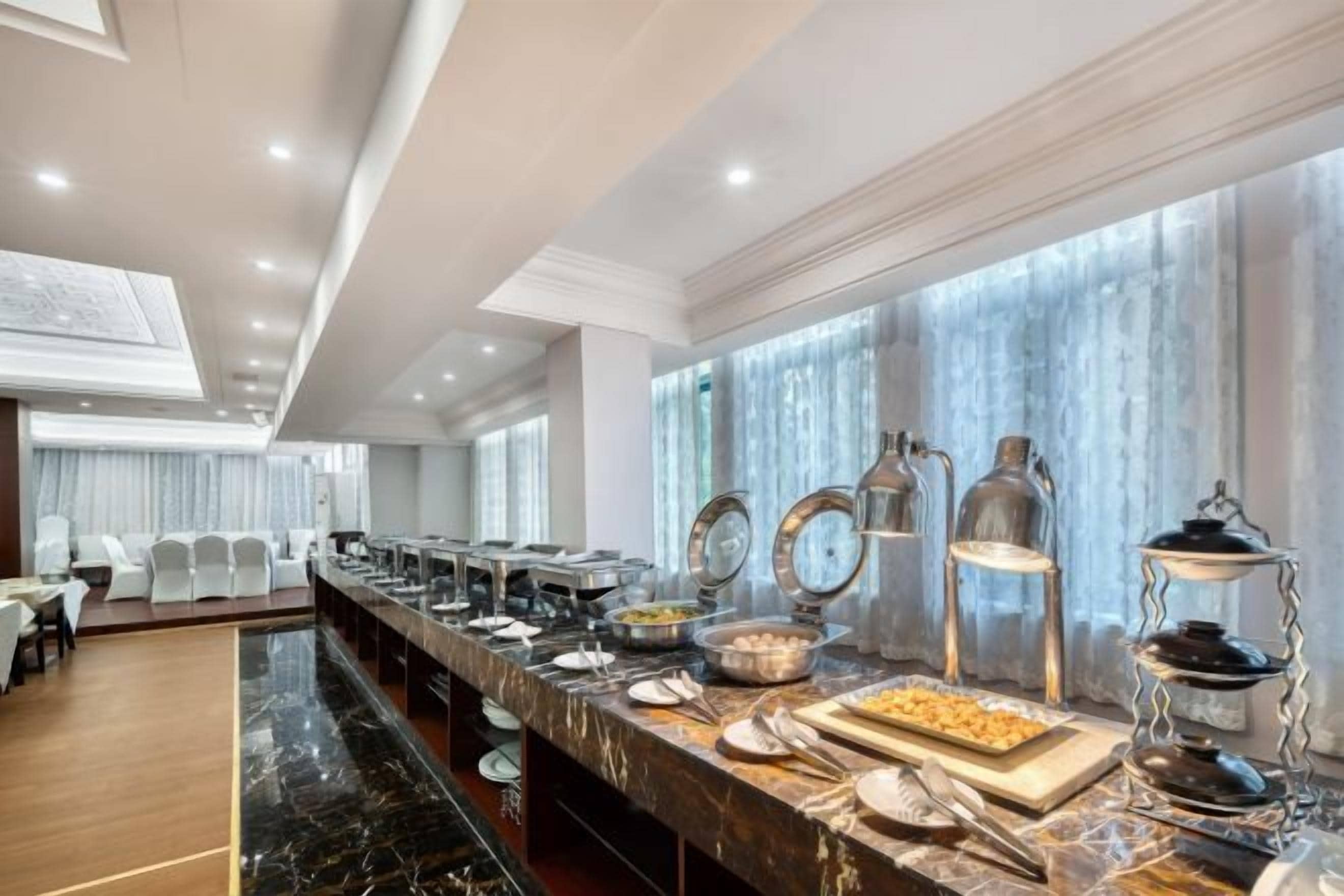 A buffet setup with various food stations, a marble countertop, and a seating area with chairs.