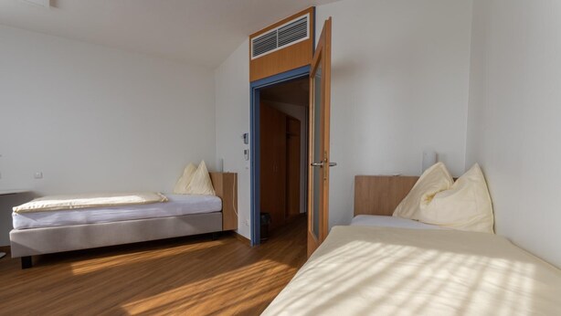 A room with two beds, a wardrobe, and a door leading to another room. - Sommerhaus Linz (Linz)