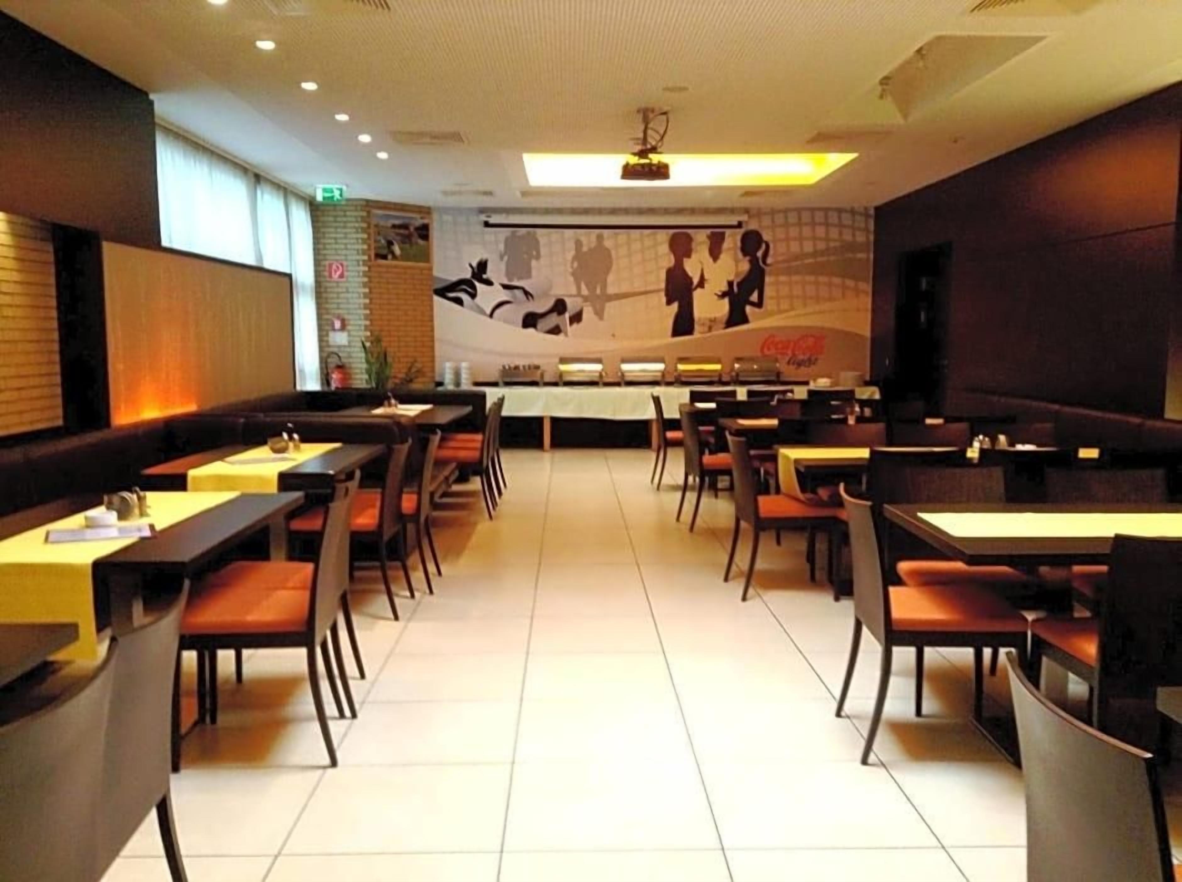 A restaurant with booths and tables, a mural on the wall, and a Coca-Cola logo.