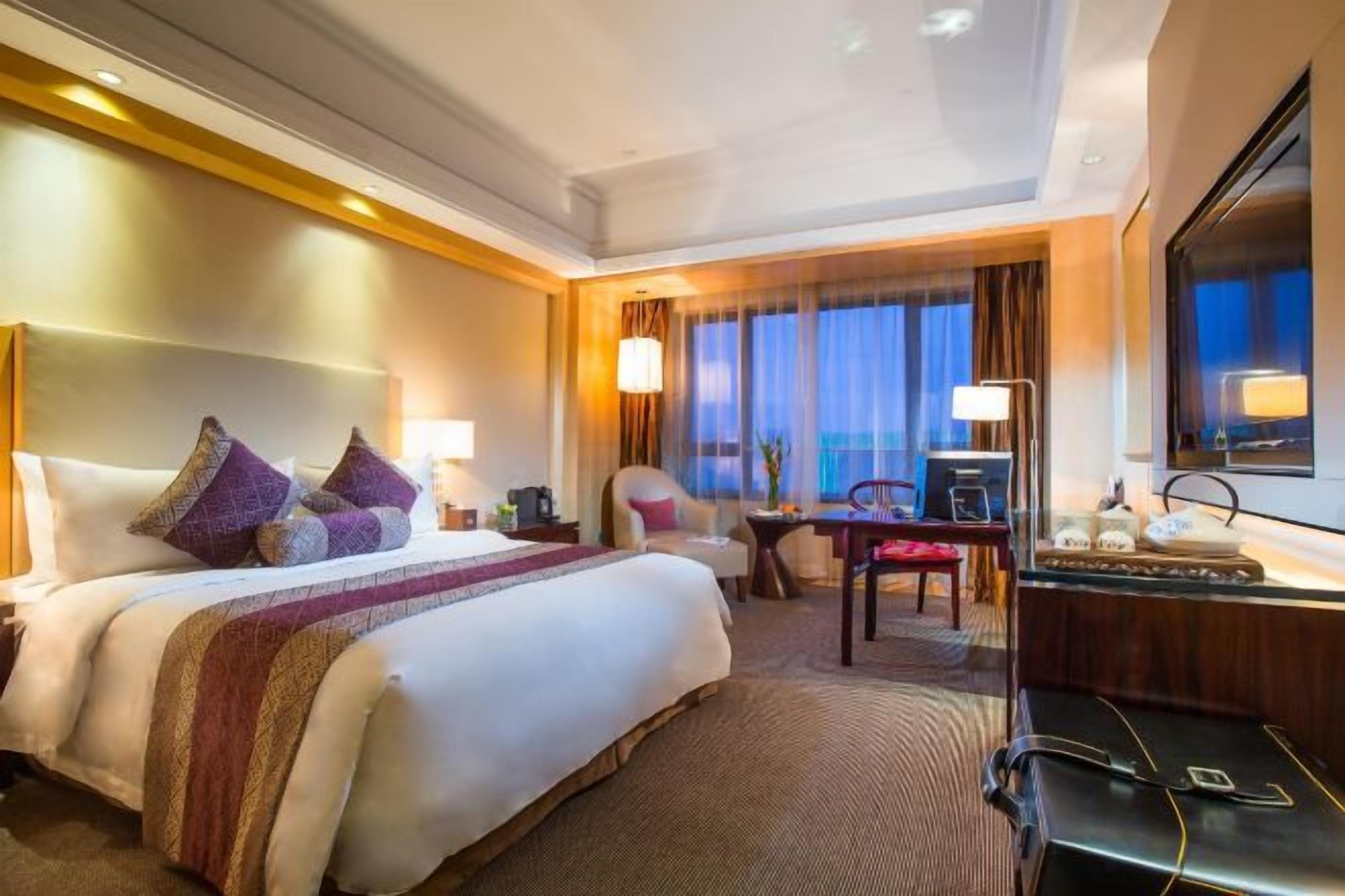 Una habitación de hotel con una cama grande, un escritorio, una silla y un televisor.