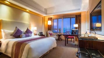Una habitación de hotel con una cama grande, un escritorio, una silla y un televisor.