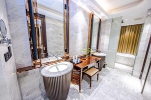 Un baño moderno con suelo de mármol, tocador de madera, un espejo grande y una cortina dorada.