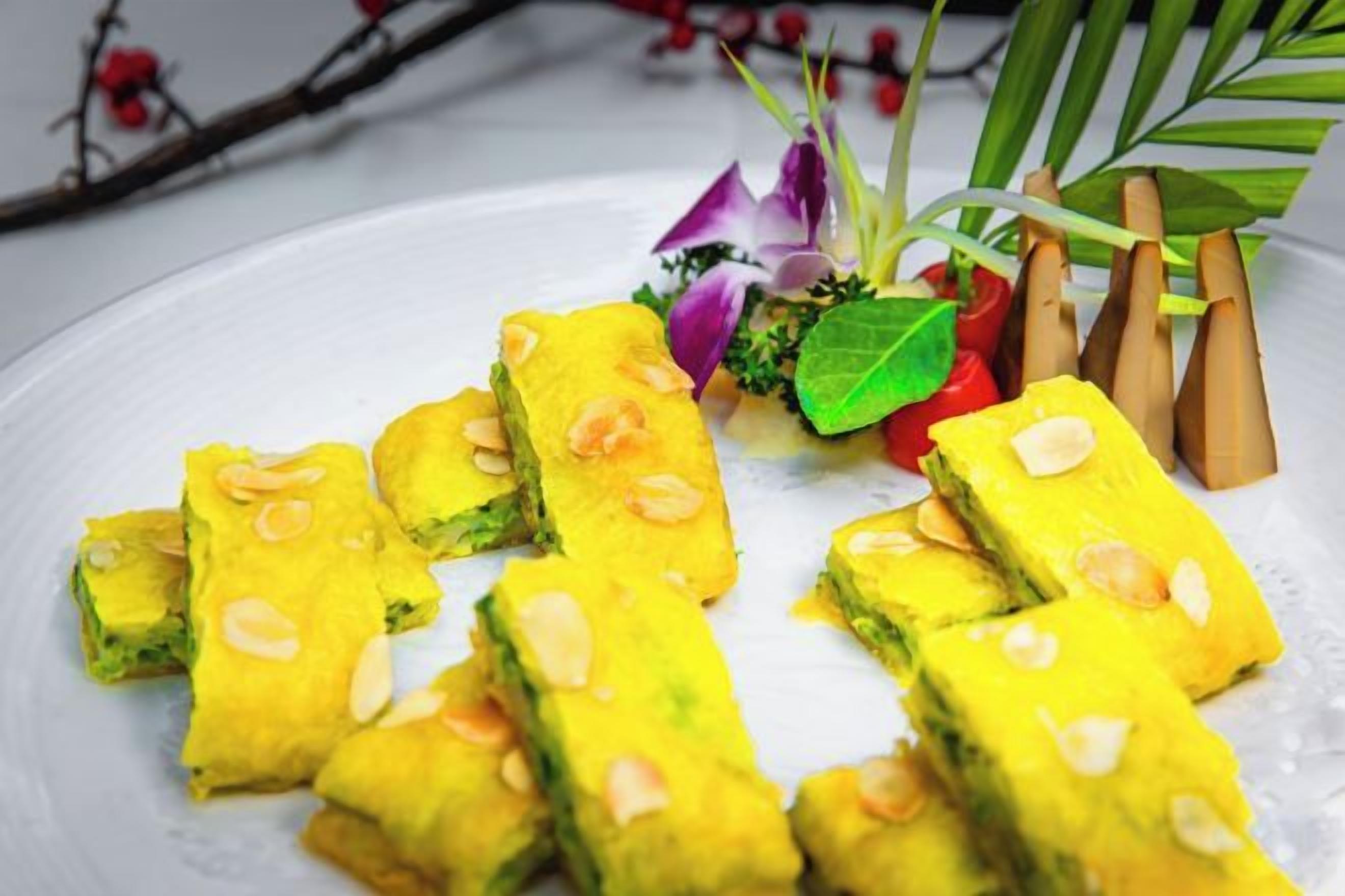 A plate of rectangular pastries with nuts on a white surface, accompanied by decorative elements.