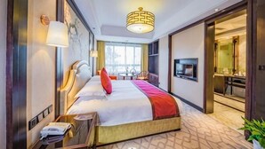 Ein Hotelzimmer mit einem großen Bett, Nachttisch, Lampe und einem Fernseher.