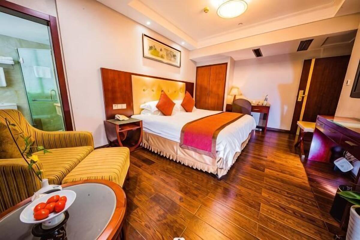 Una habitación de hotel con cama, escritorio, sillón, sofá y mesa de comedor.