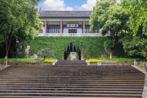 Un edificio tradicional con tejado de tejas, rodeado de vegetación y una escalera de piedra que lleva a un portón.