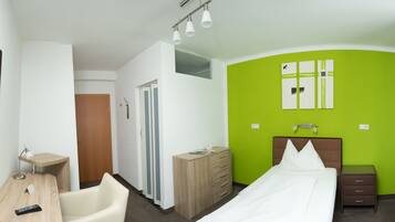 Ein Hotelzimmer mit Bett, Nachttisch, Lampe, Kommode und einem Spiegel an der Wand.