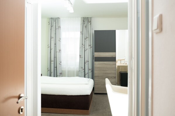 A hotel room with a bed, a desk, and a chair.