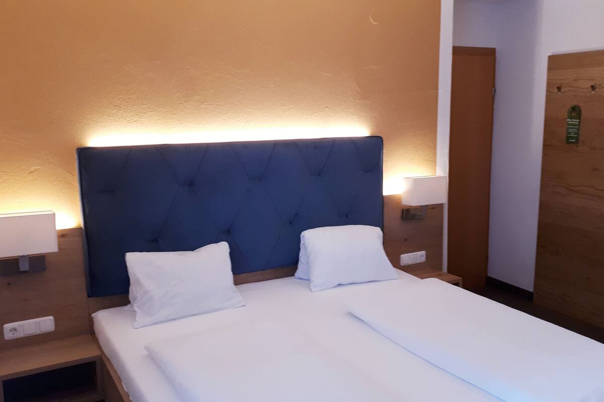 Una habitación de hotel con una cama grande, dos mesitas de noche y una puerta de madera.