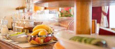 A buffet area with a variety of food items, including fruits and dishes in a glass display case.