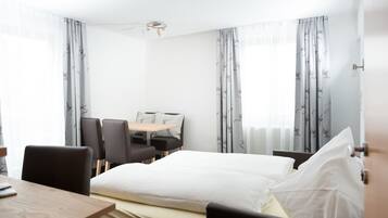 Una habitación de hotel con una cama, un escritorio y sillas, y cortinas.