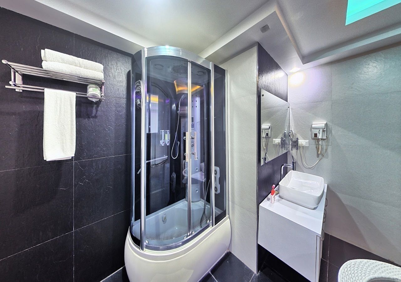 A modern bathroom with a glass-enclosed shower, a white sink, and a towel rack.