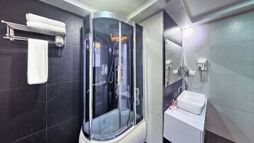 A modern bathroom with a glass-enclosed shower, a white sink, and a towel rack.