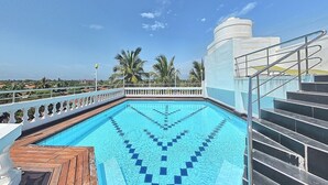 En swimmingpool med ett trädäck och en trappa som leder upp till en vit byggnad.