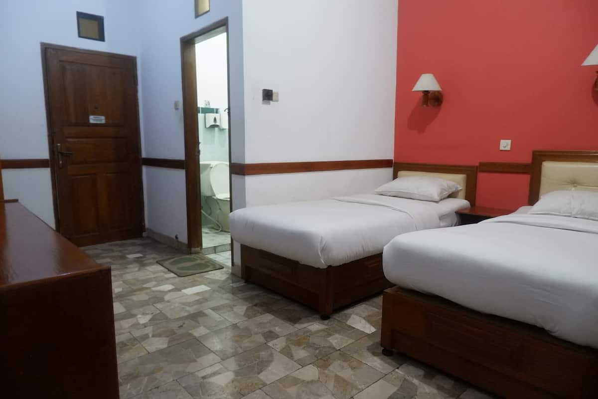A hotel room with two beds, a wooden door, a red wall, and a tiled floor.