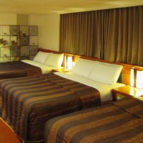 Una habitación de hotel con dos camas, una mesita de noche y un panel decorativo en la pared.