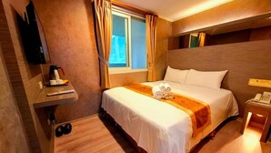 Una habitación de hotel con cama, una mesita de noche con teléfono, una pequeña mesa con cafetera y una ventana con cortinas.