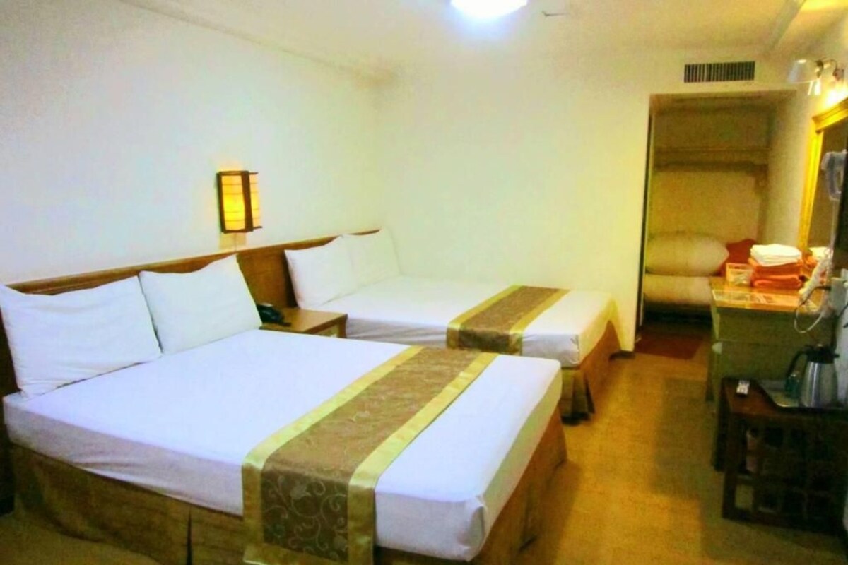 Une chambre d’hôtel avec deux lits, une table de chevet avec une lampe et une chaise avec une petite table.