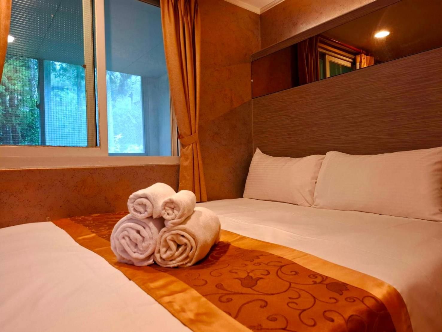 A hotel room with a bed, a window, and a view of trees.