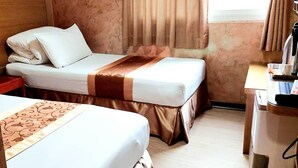 Habitación de hotel con dos camas, un escritorio con computadora y una ventana con cortinas.