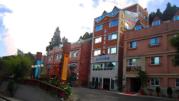 Un edificio de varios pisos con fachada de ladrillo rojo, múltiples ventanas y señalización que indica que es un hotel.