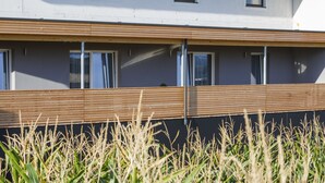A modern building with a flat roof, large windows, and a wooden deck area. - Pension Jageredt (Nussbach)