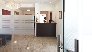 A hotel reception area with a modern design, featuring a marble floor, a chandelier, and a reception desk. - Pension Jageredt (Nussbach)