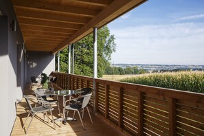 A wooden deck with outdoor furniture, overlooking a field and distant landscape. - Pension Jageredt (Nussbach)