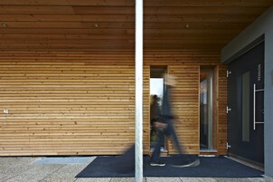 A modern building with wooden paneling and a glass door labeled "PENSION."