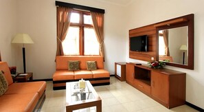A furnished living room with a sofa, a coffee table, a TV, and a cabinet. - Karang Setra (Bandung)