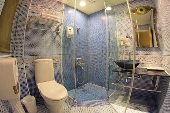 Un baño con inodoro, ducha de vidrio y lavamanos con espejo.