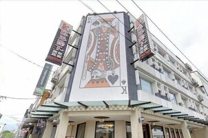 Fachada de edificio con un diseño de carta de juego grande, varios balcones y señalización comercial.