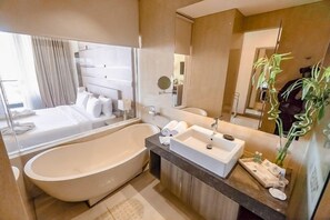 A modern bathroom with a large bathtub, a separate sink, and a mirror.