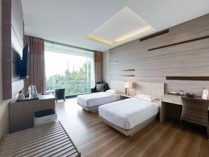 A hotel room with two beds, a desk, a TV, and a large window.