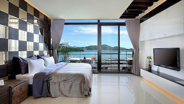 A modern bedroom with a large bed, a TV, and a balcony with a view of the sea. - LakeView Homestay (Yuchi)